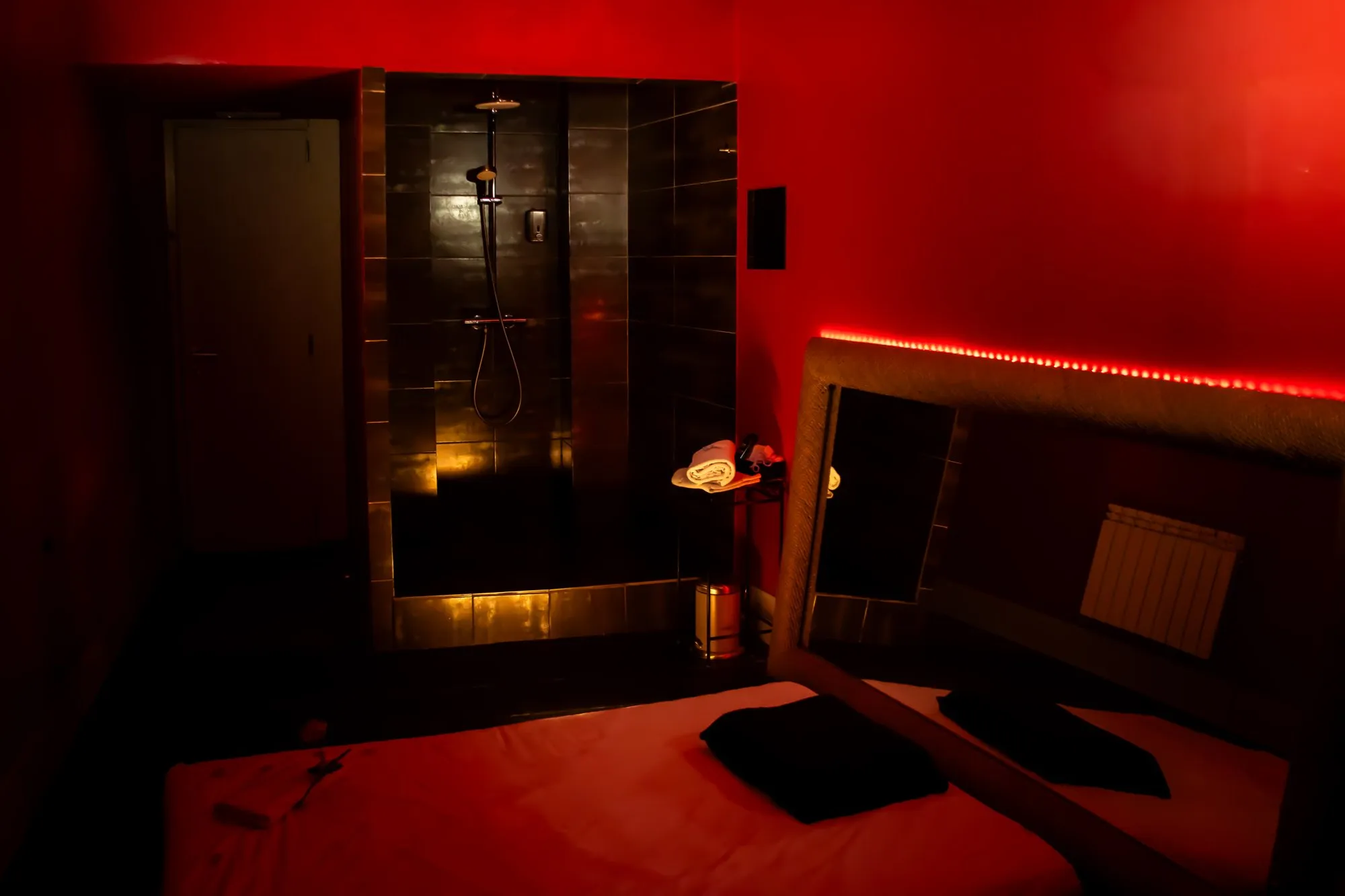 Luz roja, gran espejo con luz led y ducha de obra dentro de la sala.